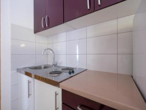 uma cozinha com um lavatório e paredes em azulejos brancos em Cozy apartment with breakfast on request 1 em Pula