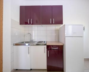 uma cozinha com armários roxos, um lavatório e um frigorífico em Cozy apartment with breakfast on request 1 em Pula