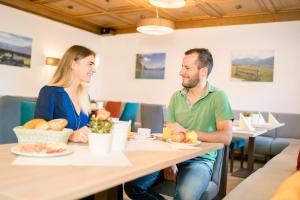 a man and woman sitting at a table in a restaurant at Hotel-Garni Schernthaner in Sankt Gilgen