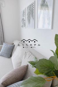 un sofá con almohadas y cuadros en la pared en OUCHI HOTEL Miyajimaguchi, en Hatsukaichi