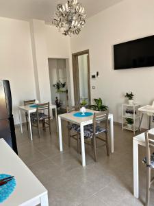 a dining room with tables and chairs and a flat screen tv at L’Angolo Chiaro in Taviano
