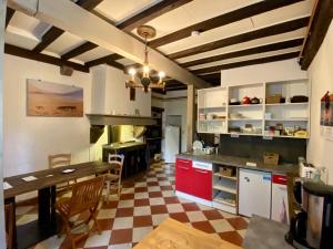 a large kitchen with red cabinets and a checkered floor at Gite de la Porte Saint Jacques: a hostel for pilgrims in Saint-Jean-Pied-de-Port