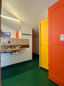 a bathroom with two sinks and a yellow door at Gite de la Porte Saint Jacques: a hostel for pilgrims in Saint-Jean-Pied-de-Port