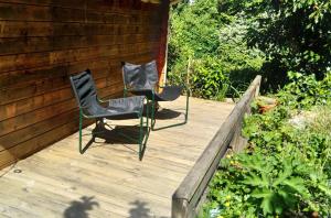 2 chaises assises sur une terrasse en bois dans l'établissement Chalet indépendant proche centre ville, au Mans