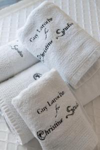 Vier weiße Handtücher mit Handschrift darauf liegen auf einem Bett. in der Unterkunft Christine Studios in Poros