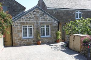 a stone house with white windows and a patio at Bryher Cottage in Paul