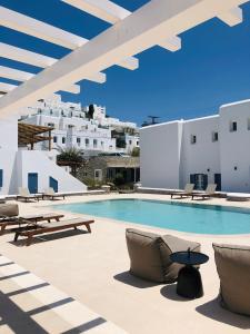 a swimming pool with chairs and tables and white buildings at Esperides in Platis Yialos Mykonos