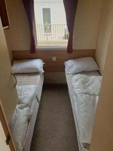 - 2 lits dans une petite chambre avec fenêtre dans l'établissement Hill View caravan, à Aberystwyth