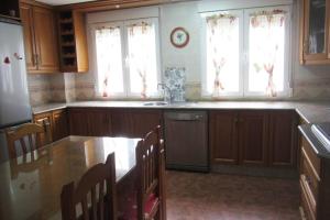 a kitchen with wooden cabinets and a sink and windows at Casa rural a 20 minutos de la Alhambra in Granada