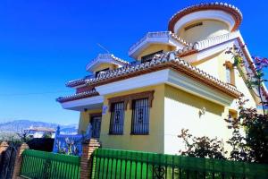 ein gelbes und weißes Haus mit einem grünen Zaun in der Unterkunft Casa rural a 20 minutos de la Alhambra in Granada