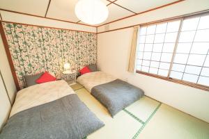 Duas camas num pequeno quarto com uma janela em Guesthouse NUI okhotsk #NU1 em Abashiri