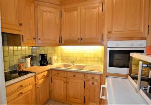 une cuisine avec des armoires en bois, un évier et un micro-ondes dans l'établissement Résidence du Mont-Blanc n°5Bis, à Combloux