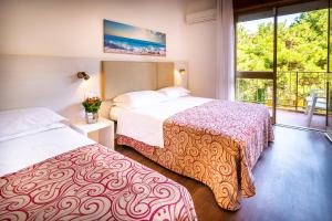 una camera d'albergo con due letti e una finestra di Hotel Niagara a Lignano Sabbiadoro Altre 38 foto