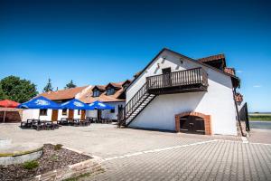 a building with a balcony and tables and blue umbrellas at Penzion Zlaté Slunce in Chocenice
