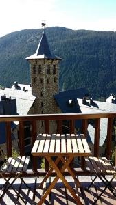 a wooden picnic table on a deck with a tower at Apartamentos Tanau in Baqueira-Beret