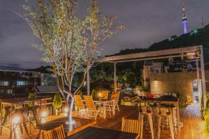 a patio with tables and chairs on a roof at night at Myeongdong Artmonstay in Seoul