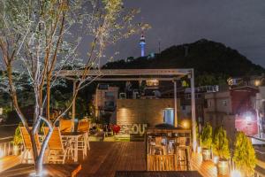 a rooftop deck with a view of the space needle at night at Myeongdong Artmonstay in Seoul