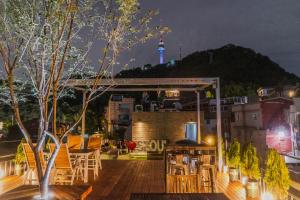 una terraza en la azotea con vistas a la aguja espacial por la noche en Myeongdong Artmonstay en Seúl