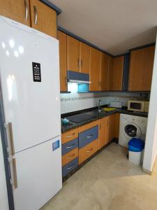 a kitchen with wooden cabinets and a white refrigerator at Bonito Apartamento Vacacional in Motril