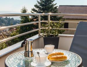a table with two pastries and coffee cups on a balcony at Apartmani Škopac Rabac in Rabac