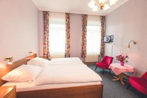 - une chambre avec un lit et une chaise rouge dans l'établissement Rheinhotel Starkenburger Hof, à Bingen am Rhein