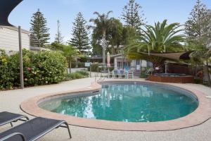 a swimming pool in a yard with chairs and trees at Bayview Apartments by Classic Holidays in Cowes