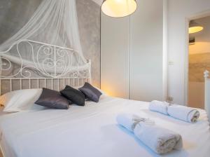 a bedroom with a white bed with towels on it at Apartmani Škopac Rabac in Rabac