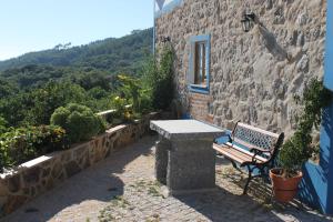 a bench sitting next to a stone building with a window at Horta do Zé Miguel in Monchique