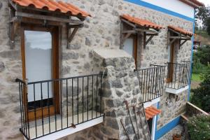 a stone house with a porch and a balcony at Horta do Zé Miguel in Monchique