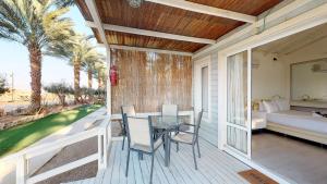 una veranda con tavolo e sedie e una camera da letto di Shkutai Hottub Arava a Ẕofar Altre 37 foto