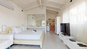 a white room with a bed and a tv at Shkutai Hottub Arava in Ẕofar