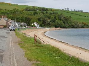a beach with a car parked next to the water at Pleasant Point Holiday Cottages in Rosemarkie