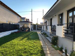 einen Hinterhof eines Hauses mit Rasen in der Unterkunft Vila Blanc in Costinești
