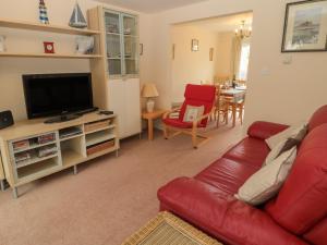 a living room with a red couch and a television at 3 Kings Field in Seahouses
