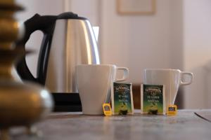 two cups of coffee sitting on a counter next to a kettle at Città Di Castello Rooms in Città di Castello
