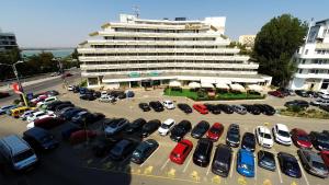 un estacionamiento con autos estacionados frente a un edificio en Hotel Condor, en Mamaia