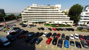 a parking lot with cars parked in front of a building at Hotel Condor in Mamaia