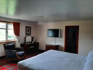 a hotel room with a bed and a flat screen tv at Laggan Hotel in Laggan