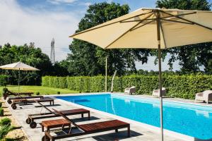 einem Pool mit Bänken und einem Sonnenschirm daneben in der Unterkunft Moslavačka Priča Holiday Homes in Mala Ludina