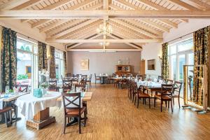 un comedor con mesas, sillas y ventanas en Adler Landhotel, en Buergstadt