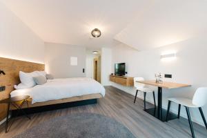 a bedroom with a bed and a desk and a television at Modernes Appartment BlackForest Art 35 qm Nähe Freiburg in Simonswald