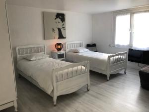 2 weiße Betten in einem Zimmer mit einem Wohnzimmer in der Unterkunft 61 BIS ST GEORGES DE DIDONNE in Saint-Georges-de-Didonne