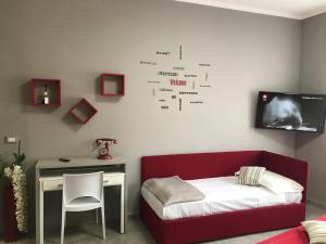 a room with a bed and a desk and a tv at HappyHome Monolocale Rivarolo Canavese in Rivarolo Canavese