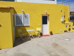 ein gelbes Gebäude mit einem Tisch und Stühlen davor in der Unterkunft La casita de Candida in Tigaday
