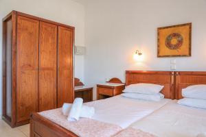 a bedroom with two beds with white sheets and wooden furniture at Pandora Studios Skiathos in Skiathos