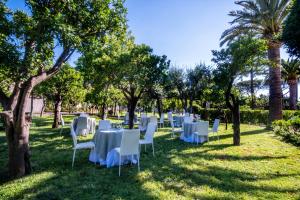 a group of tables and chairs in the grass with trees at Hotel Alpha in Sant'Agnello