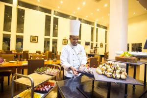 a chef standing in a restaurant with a tray of food at Grand Tamarind Lake in Kataragama