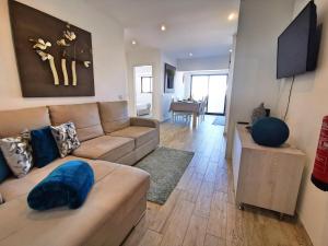 uma sala de estar com um sofá e uma televisão de ecrã plano em Apartment Praia Rocha Waterside Blue em Portimão