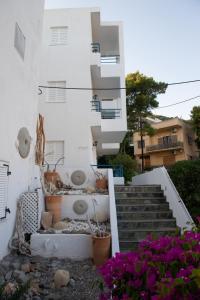 a white building with stairs and flowers in front of it at Christine Studios in Poros