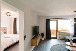 a bedroom with a bed and a tv and a couch at Moderne 2 Zi.-FeWo BlackForest Art Barrierefrei Nähe Freiburg in Simonswald
